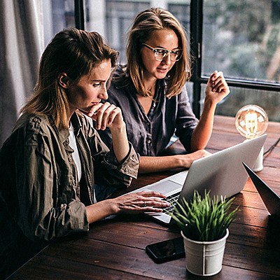 two women at a desk looking at a laptop