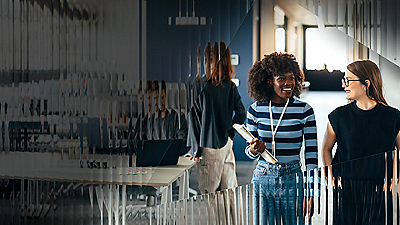 A group of coworkers stands together in a contemporary office space, engaged in conversation.