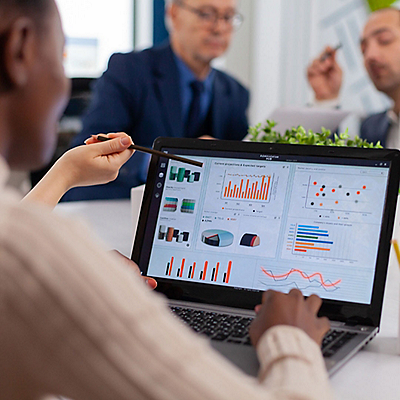 A person looking her laptop and working on statistics and graphs of data.