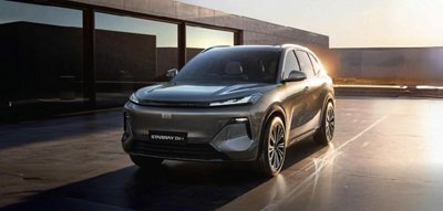 A sleek, modern SUV is parked on a reflective surface in front of a contemporary glass building.