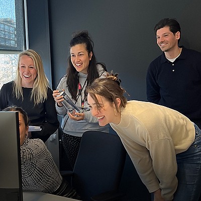 Group of people looking at a screen and smiling.