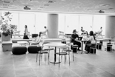 people sitting at tables in open office space in front of windows