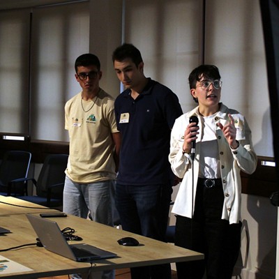two men and a woman with glasses standing conducting a presentation