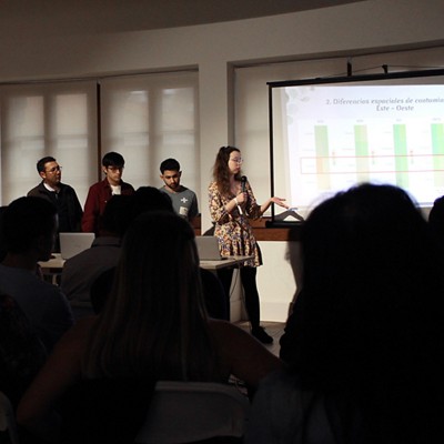 Four people standing, giving a presentation with a projector showing a graph chart