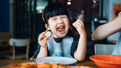 Female child eating sandwiches in a high chair and smiling
