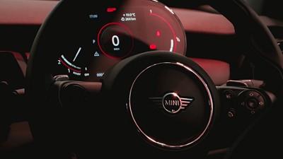 Mini steering wheel and dashboard showing speedometer panel in the background
