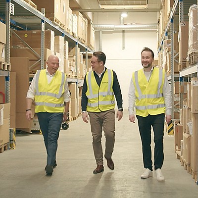 Three man walking around the stockroom in yellow vests