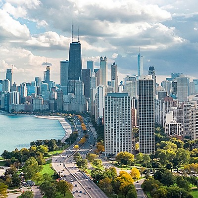 Aerial view of Chicago skyline with tall skyscrapers, green parks, and a lakefront. 