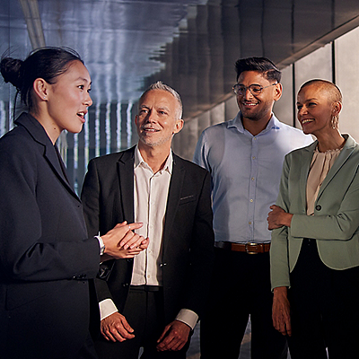 A diverse group of four professionals in formal attire are engaged in a positive discussion. 