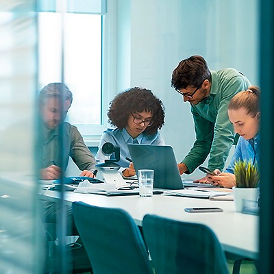 Team of professionals collaborating at a conference table with laptop and documents.