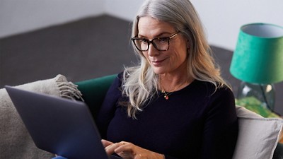 A woman wearing glasses types on her laptop