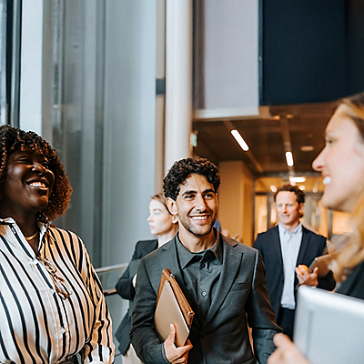 A group of professionals engaged in conversation in a modern office setting, showcasing diverse attire and interactions.