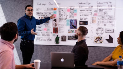 Person standing in front of whiteboard pointing at written strategy