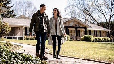 Couple walking in front of a nice home