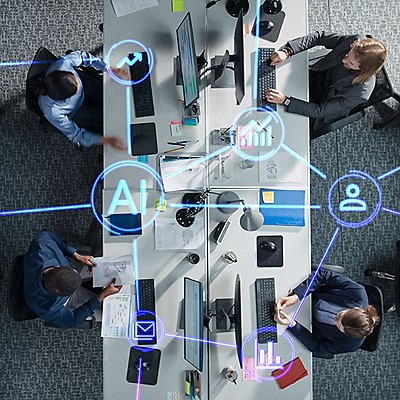 Overhead view of a modern office with three people at desks using computers, surrounded by digital icons of AI, analytics, email, and social connections.