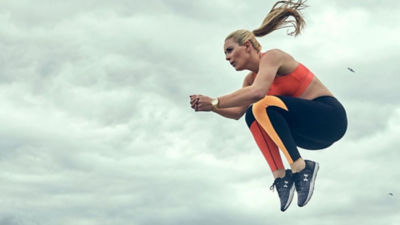 A woman wearing Under Armour apparel jumps in the air