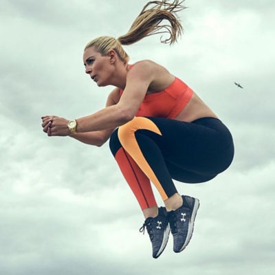 A woman wearing Under Armour apparel jumps in the air