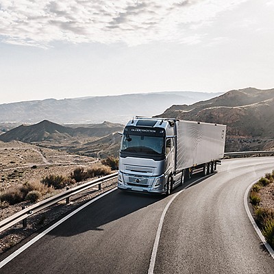 Camión Volvo en la carretera, rodeado de montañas y cielo nublado