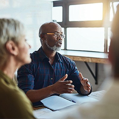 A group discussion in a well-lit room, with one participant explaining business.