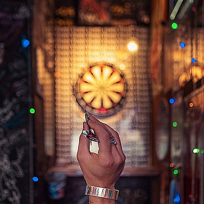 A hand prepares to throw a dart at a dart board