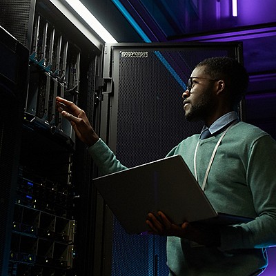 man holding a laptop and looking inside a cabinet