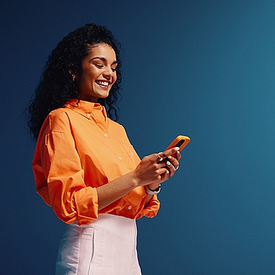 A woman scrolling through her phone with a happy grin