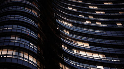 A building featuring numerous windows is depicted as a car passes by, illustrating a dynamic city scene.